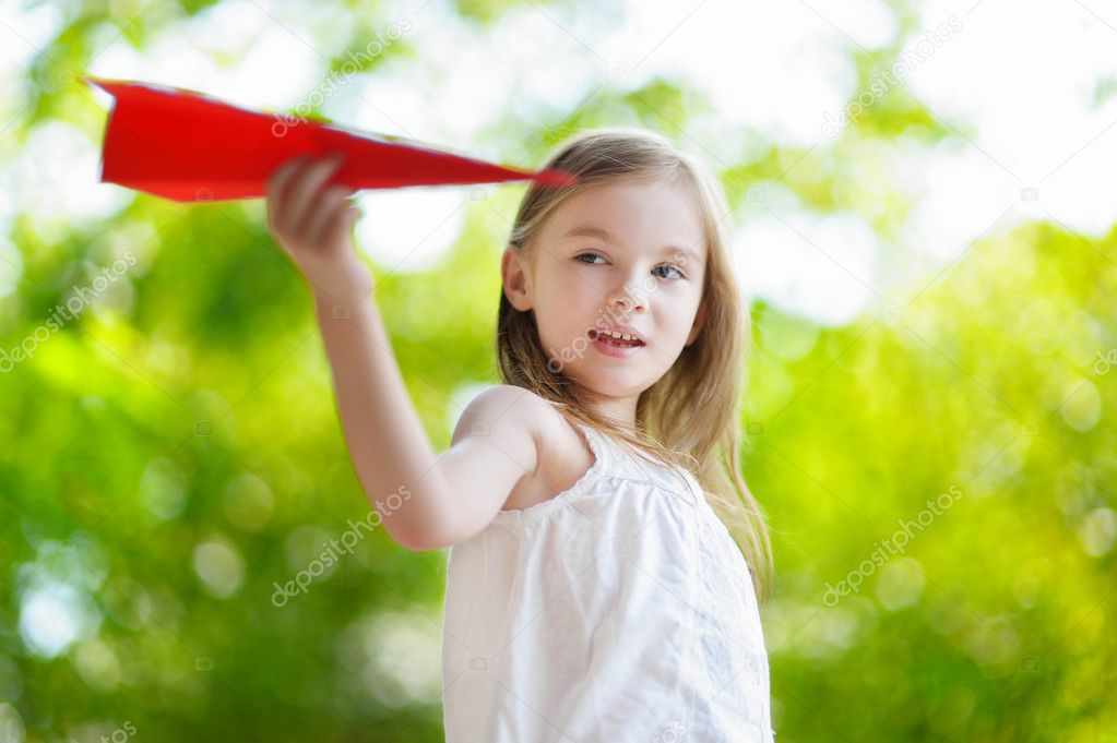 little girl holding a paper plane