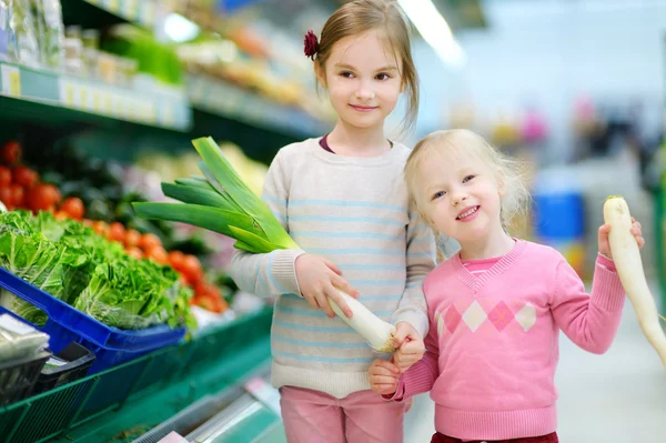 Systrarna att välja grönsaker i butik — Stockfoto