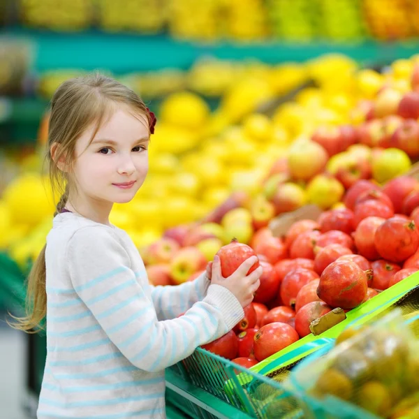 Little girl choosing pomegranate — Stock Photo, Image