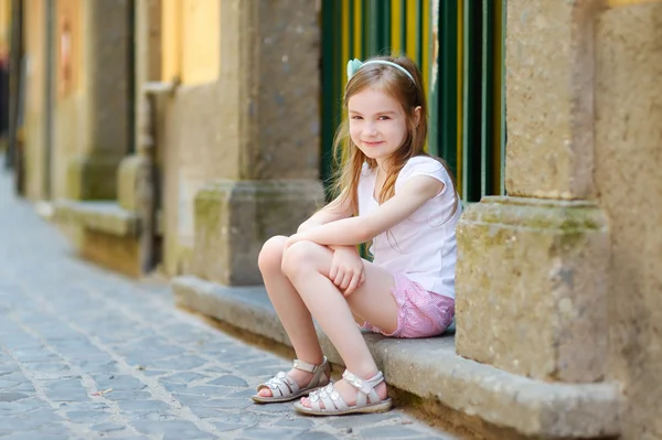 Kleines Mädchen sitzt vor der Haustür — Stockfoto