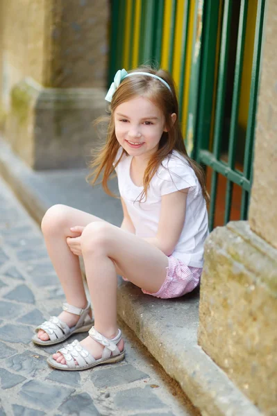 Bir kapının önünde oturan küçük kız — Stok fotoğraf