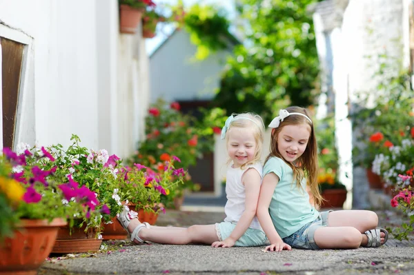 Sisters sitting among flowers — Stock Photo, Image