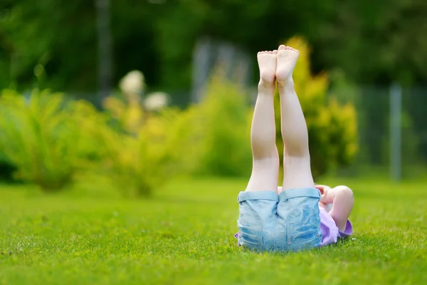 Klein meisje in het gras te leggen — Stockfoto