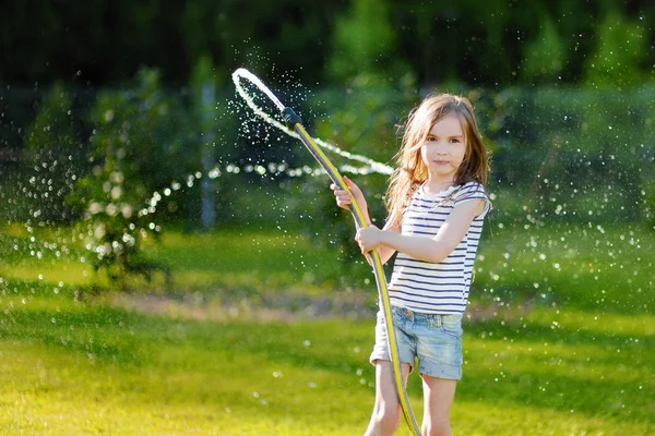 Girl playing with a garden hose — Stock Photo, Image