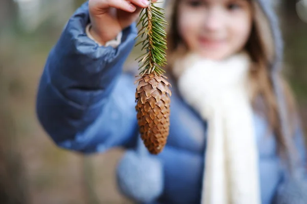 Adorable niña sosteniendo un cono de pino — Foto de Stock