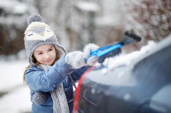 Girl helping to brush a snow — Stock Photo, Image