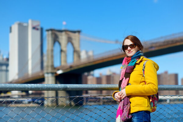 Beautiful young woman sightseeing by Brooklyn Bridge, New York, at sunny spring day