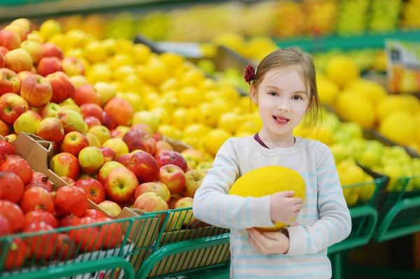 Lilla flickan att välja melon i butik — Stockfoto