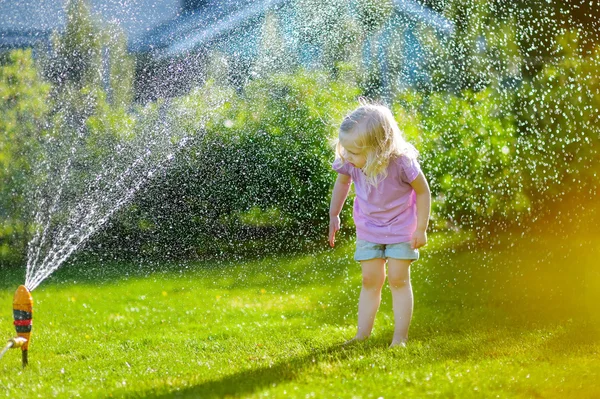 Mädchen spielt mit einem Sprinkler — Stockfoto