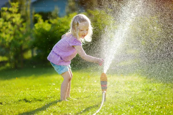 Mädchen spielt mit einem Sprinkler — Stockfoto