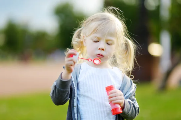 Chica soplando burbujas de jabón al aire libre — Foto de Stock