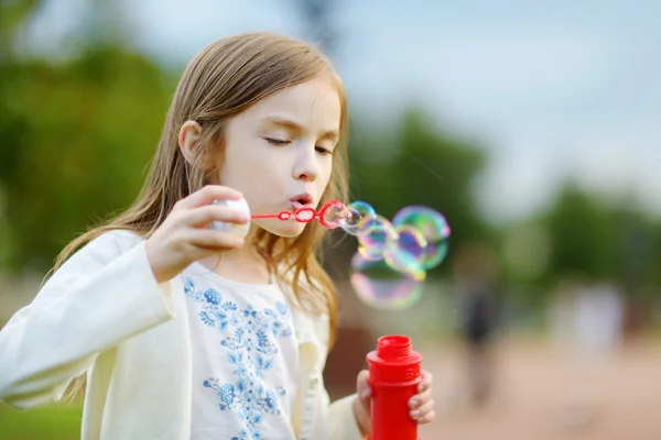 Chica soplando burbujas de jabón al aire libre — Foto de Stock