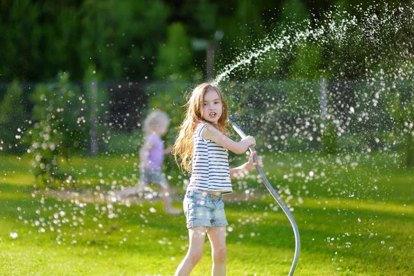 Lány játszik egy kerti locsolócsőből — Stock Fotó