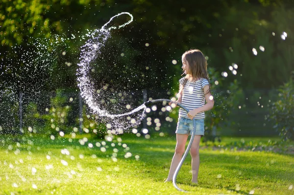 Flicka som leker med en trädgårdsslang — Stockfoto