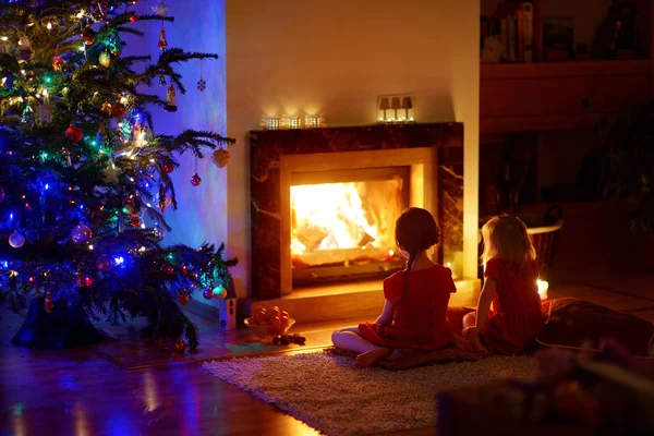 Chicas sentadas junto a la chimenea en Nochebuena — Foto de Stock