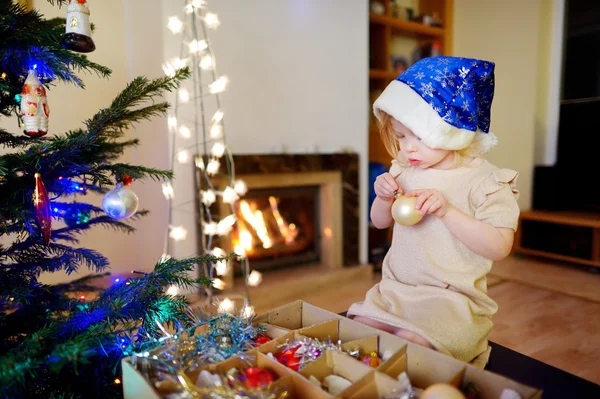 Kleines Mädchen schmückt einen Weihnachtsbaum — Stockfoto