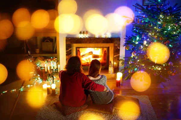 Coppia seduta accanto a un camino alla vigilia di Natale — Foto Stock