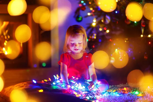 Kleines Mädchen spielt mit Weihnachtsbeleuchtung — Stockfoto