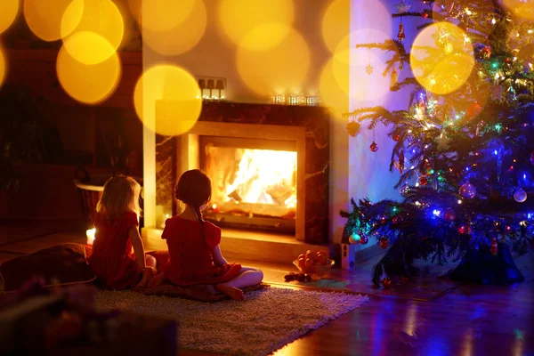 Meninas sentadas à lareira na véspera de Natal — Fotografia de Stock