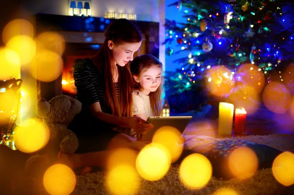 Mother and daughter using a tablet by a fireplace — Stock Photo, Image