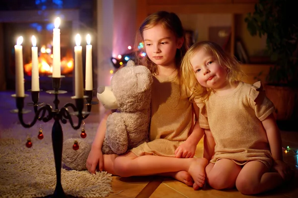 Noel arifesinde şöminenin yanında oturan kızlar — Stok fotoğraf
