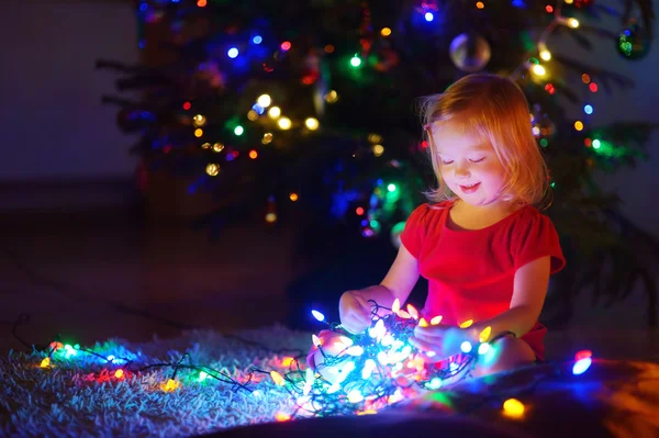 Petite fille jouant avec les lumières de Noël — Photo