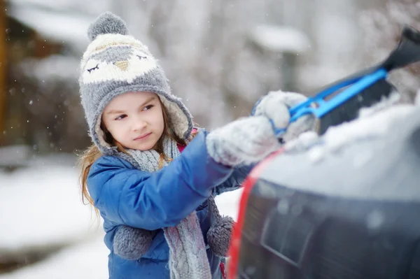 Little girl helping to brush a snow — Stock Photo, Image