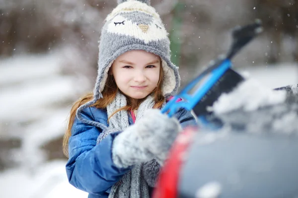 Bambina che aiuta a spazzolare una neve — Foto Stock