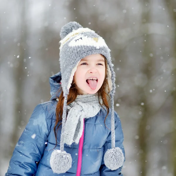 Meisje vangen sneeuwvlokken in winter park — Stockfoto