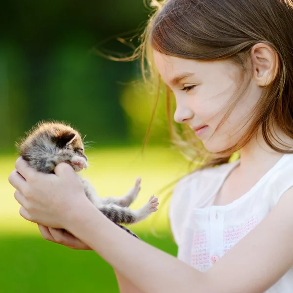 Девочка, играющая с маленьким котенком — стоковое фото