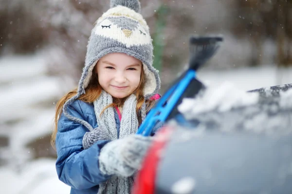 Little girl helping to brush a snow — Stock Photo, Image