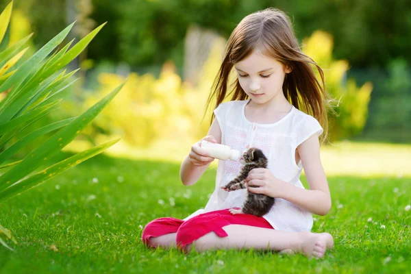 Menina alimentando pequeno gatinho com leite — Fotografia de Stock