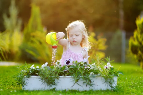 Dívka zalévání květiny na zahradě — Stock fotografie