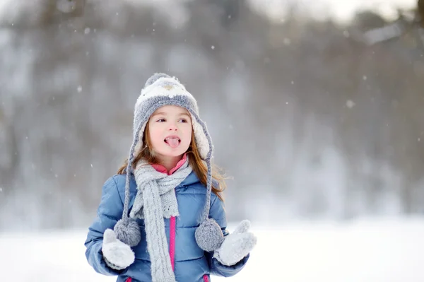 Mädchen fängt Schneeflocken im Winterpark — Stockfoto