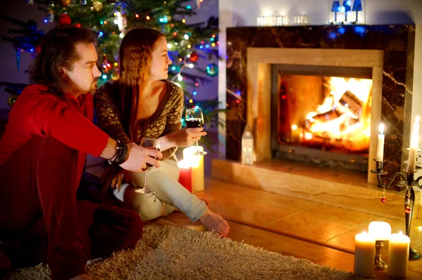 คู่รักนั่งอยู่ข้างเตาผิงในวันคริสต์มาส — ภาพถ่ายสต็อก