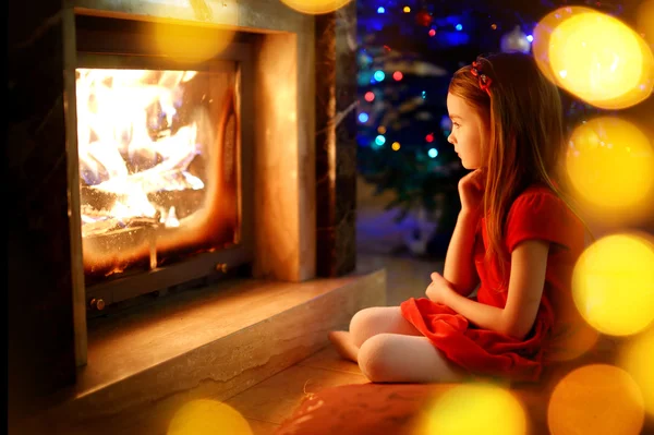Dívka sedí u krbu na Štědrý den — Stock fotografie