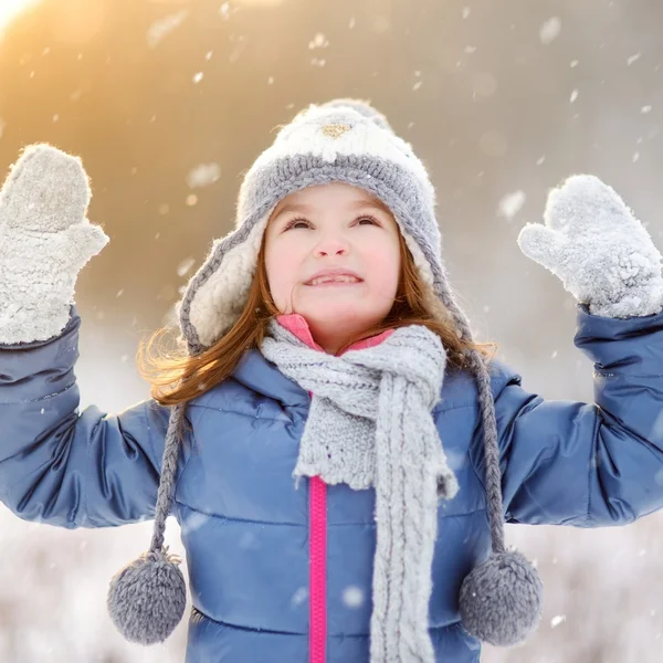 Meisje vangen sneeuwvlokken in winter park — Stockfoto