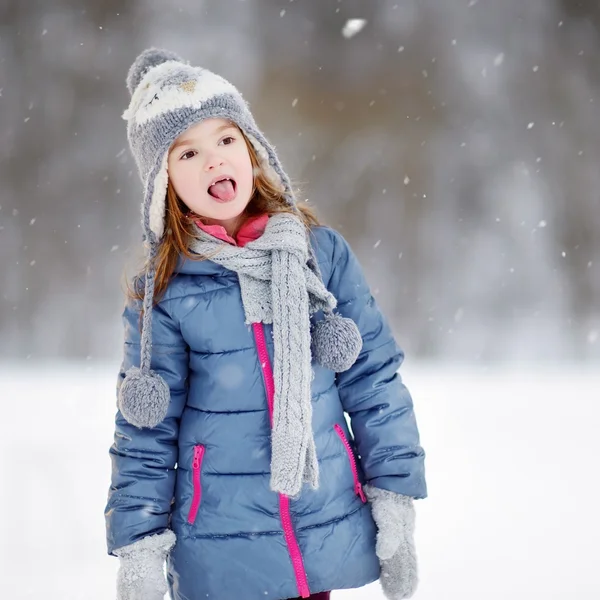 Menina pegando flocos de neve no parque de inverno — Fotografia de Stock