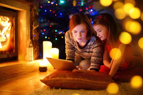 Mother and daughter using a tablet by a fireplace — Stock Photo, Image