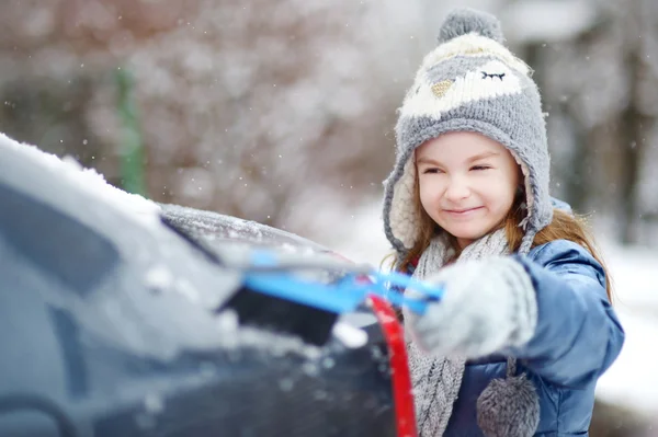 Little girl helping to brush a snow — Stock Photo, Image