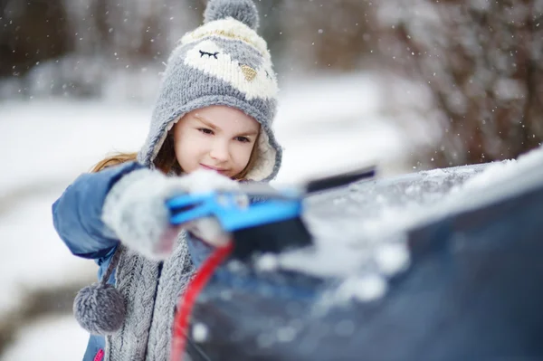 Mała dziewczynka pomaga odświeżyć śnieg — Zdjęcie stockowe