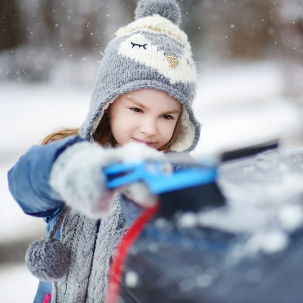 Girl helping to brush a snow — Stock Photo, Image