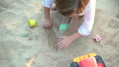 Parlak güneşli bir yaz gününde oyun alanında eğlenen sevimli küçük çocuk. Kum havuzunda oynayan sevimli bir çocuk. Çocuklu aileler için açık hava aktiviteleri.
