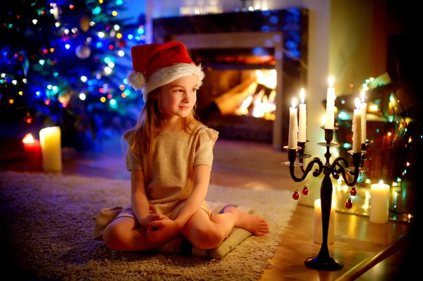 Girl sitting by a fireplace on Christmas eve — Stock Photo, Image