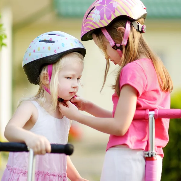 Niña ayudando a su hermana con el casco puesto —  Fotos de Stock