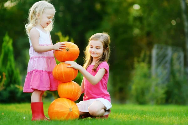 Zusters spelen met enorme pompoenen — Stockfoto