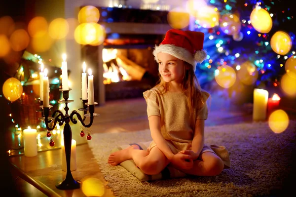 Girl sitting by a fireplace on Christmas eve — Stock Photo, Image