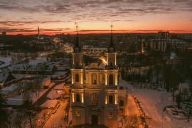 Kalvariju Kutsal Haç Keşfi Kilisesi kışın alacakaranlıkta sıcak bir şekilde parlar, yukarıdan görülür. Kutsal sakinlik, altın saat hava perspektifinde kentsel yayılımla buluşur..