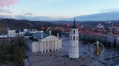 Vilnius Katedral Meydanı 'nın 2024 Noel ağacı kurulumu ve Eski Şehir' in çatıları ile akşam manzarası. Şenlikli bir şehir manzarası. Tarihi harmanlayan, kış cazibesi ve sessiz bir kutlama..
