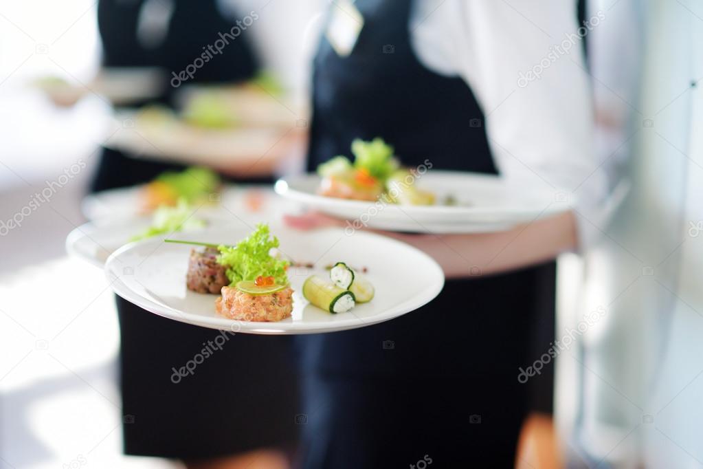 Waiters carrying plates with meat